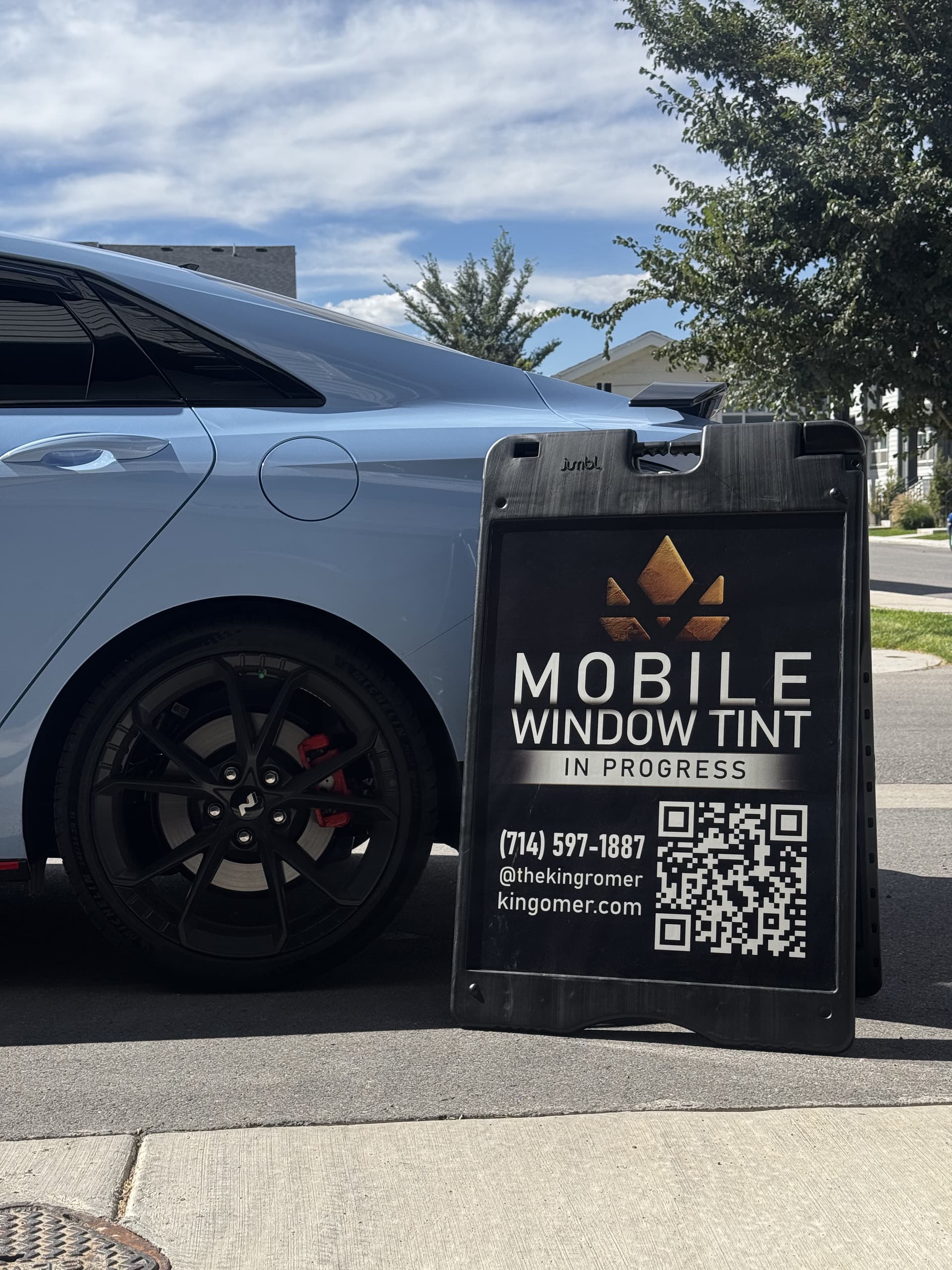 King Romer mobile window tint A-frame sign next to a car in a Utah driveway